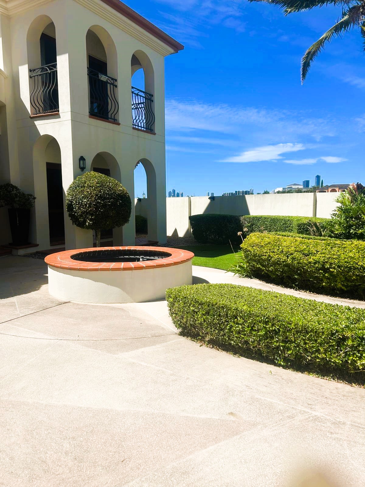 Mediterranean-style mansion with sculpted topiary ball, curved hedges, fountain feature, and manicured lawn on the Gold Coast