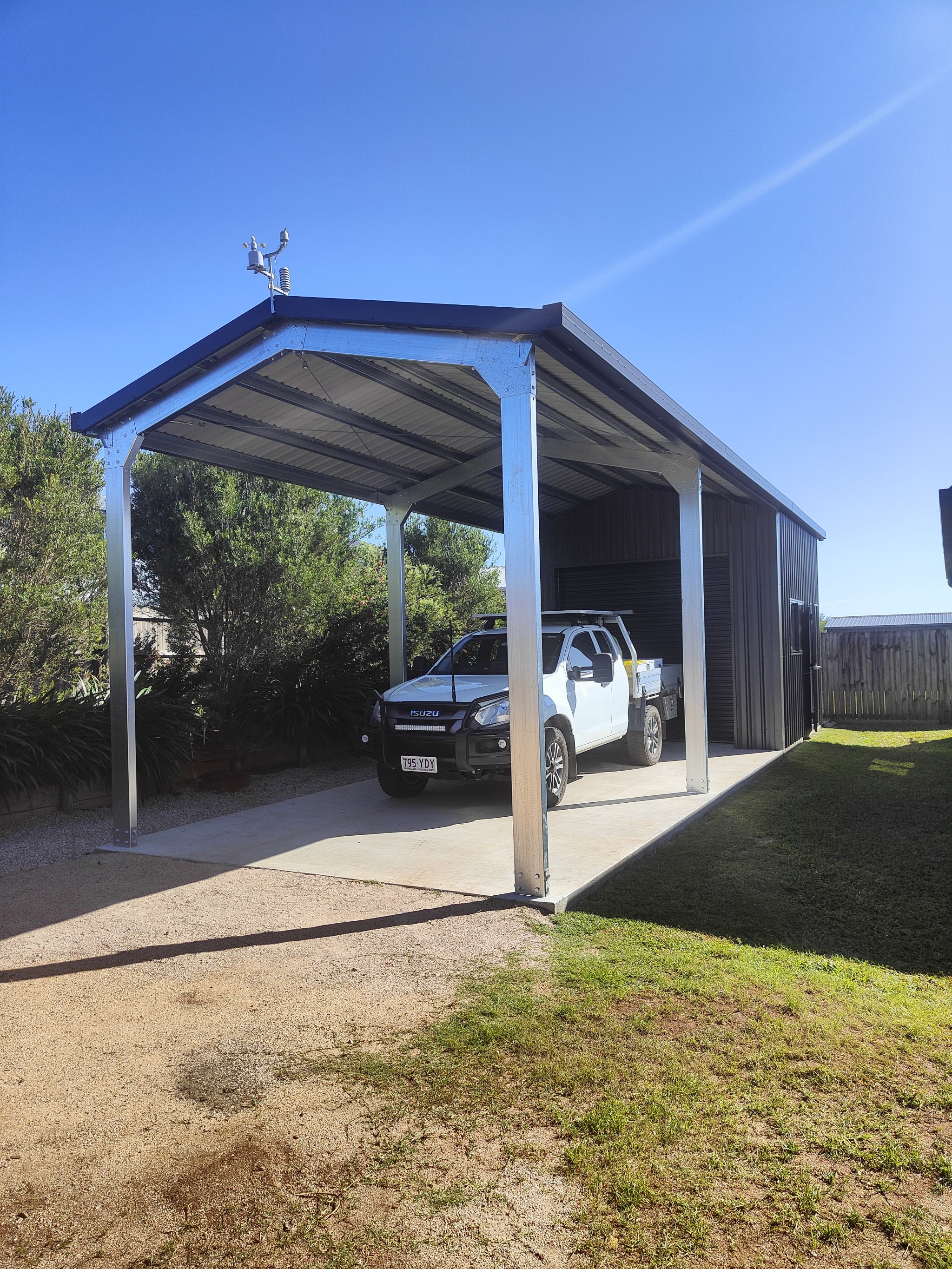 Steel garaport with an enclosed dark shed and an open covered bay with a ute parked in it