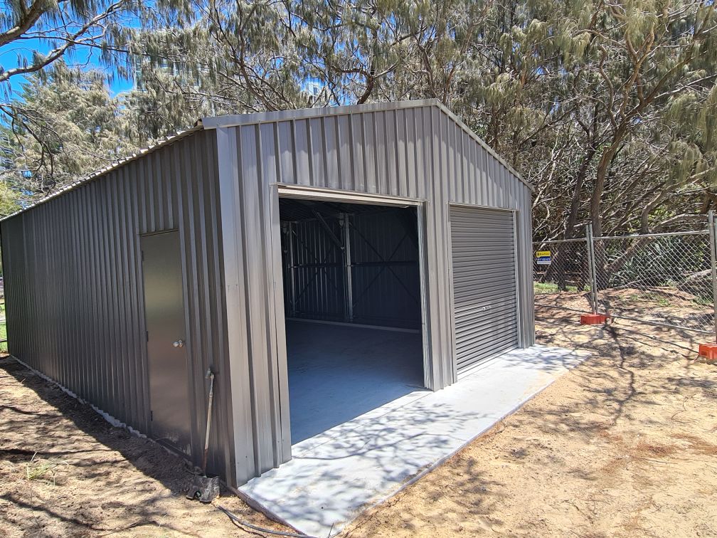 Grey steel single-bay shed with a roller door and a personal-access door