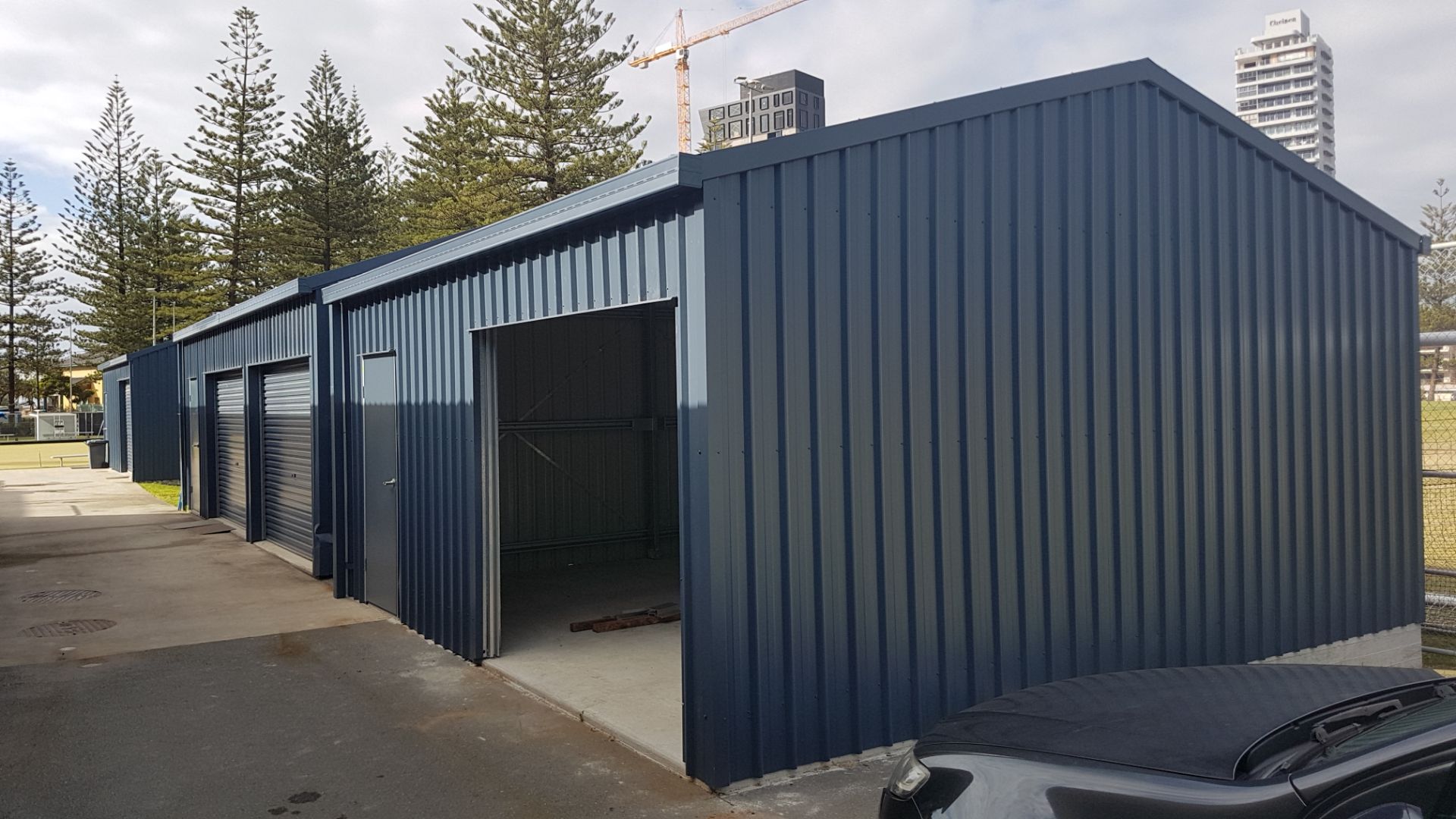 Large navy steel multi-bay building with roller doors and personal-access doors