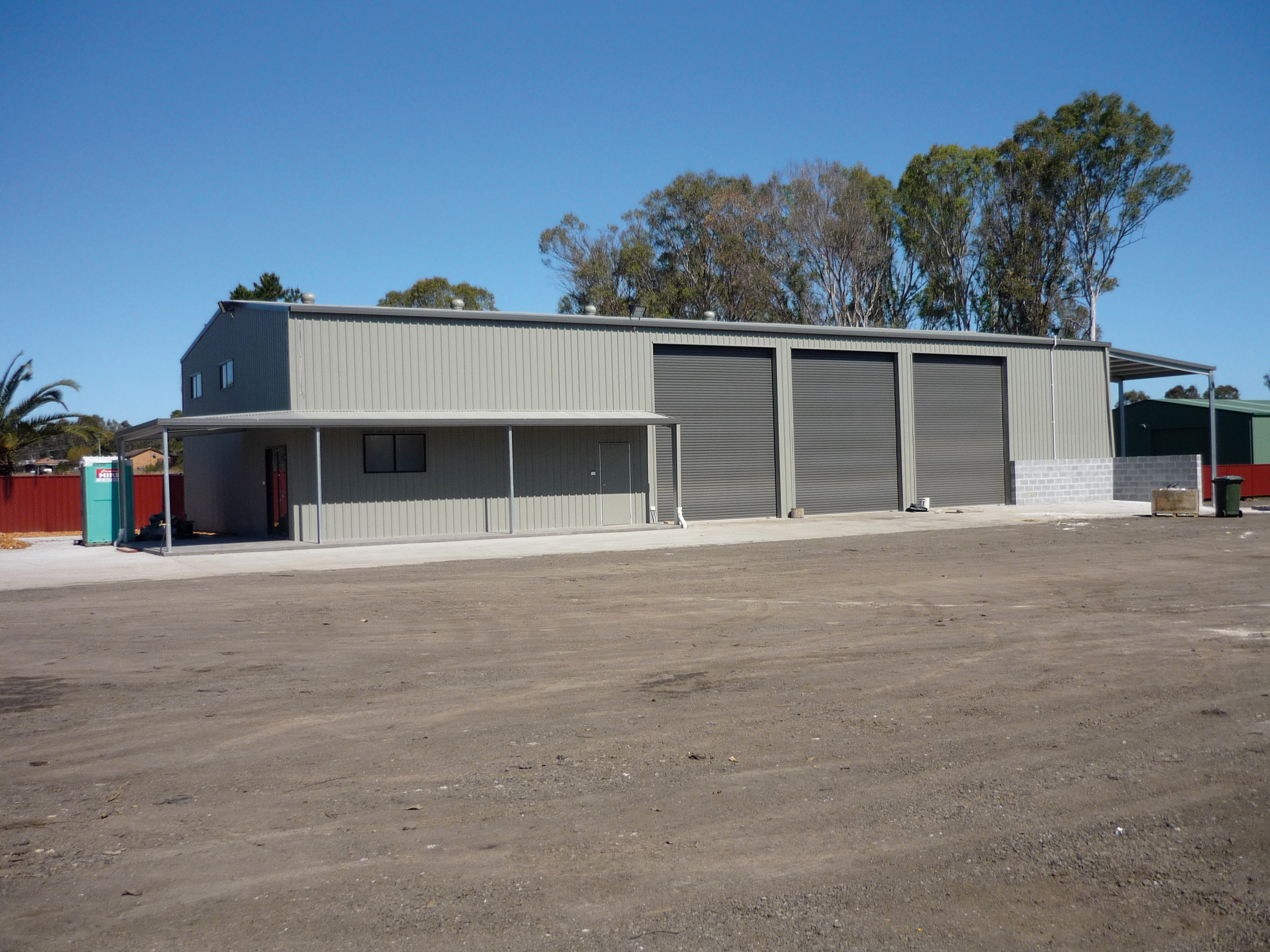 Steel building with three roller doors and a covered awning along one side