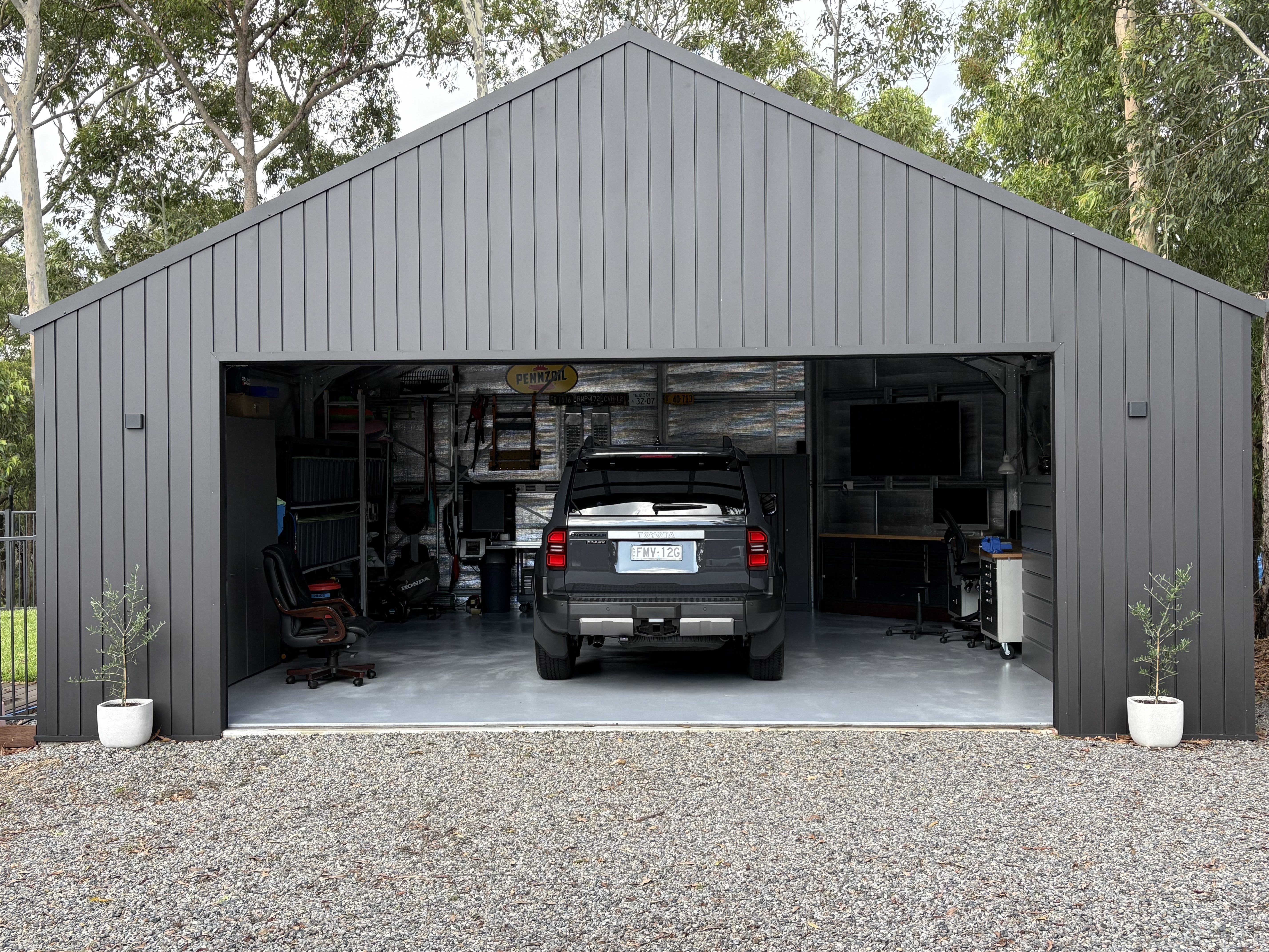 Charcoal steel garage with the door open showing a 4WD, workbench and storage inside