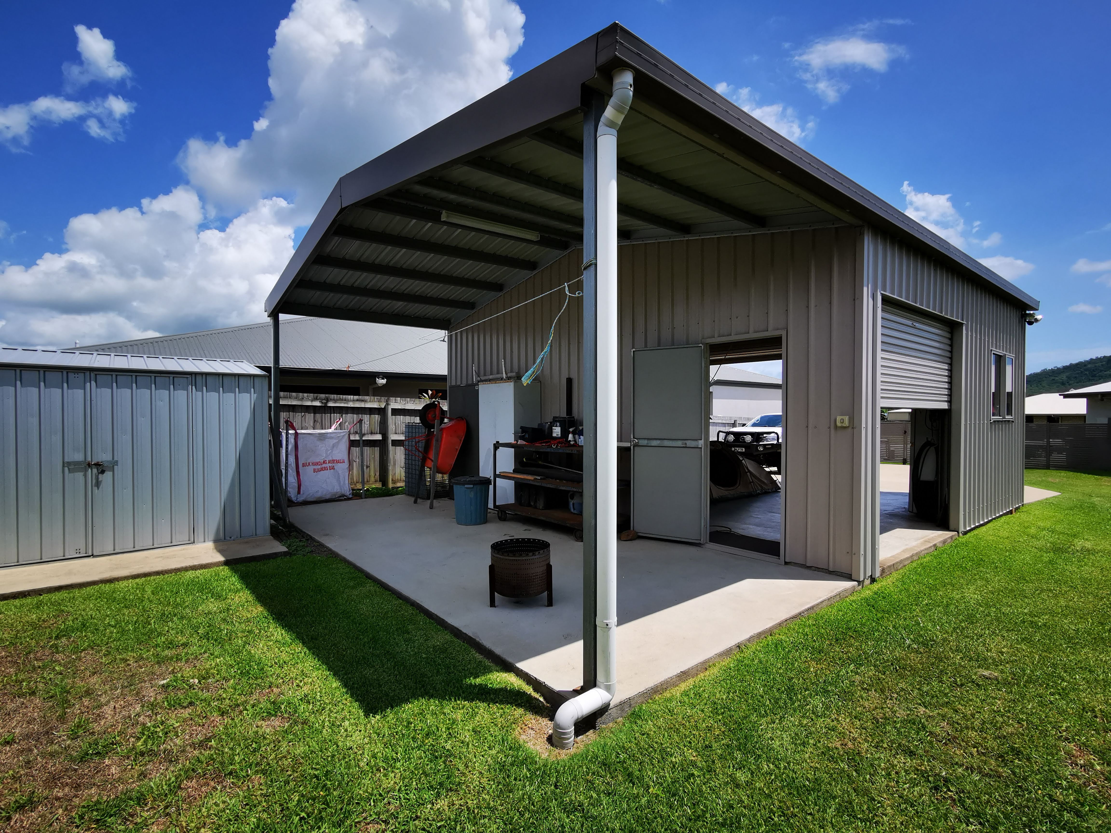 Steel garaport with an enclosed workshop and a covered open area used for storage