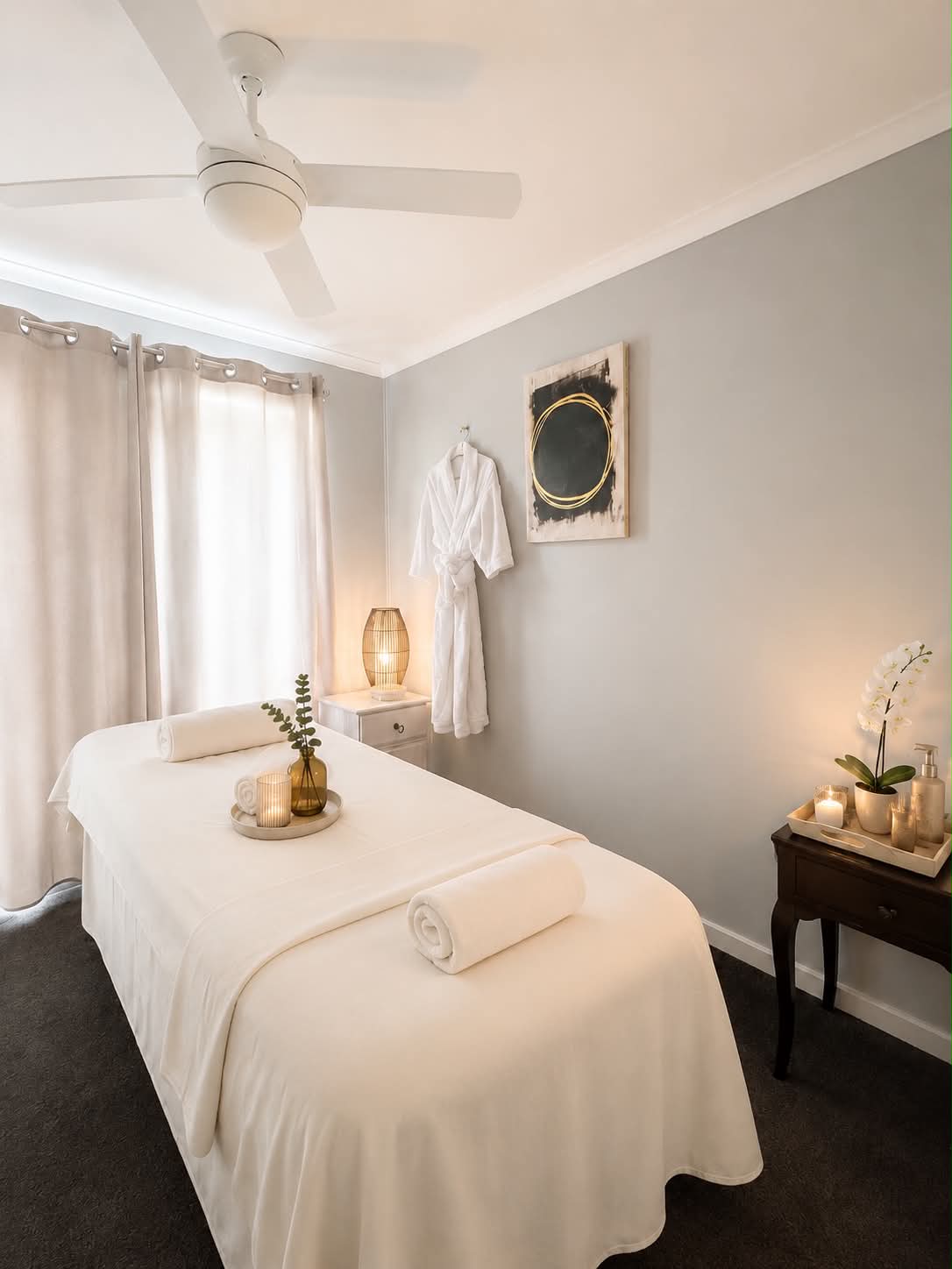Realuxe Wellness private treatment room — white massage table, robe, orchid and warm lighting
