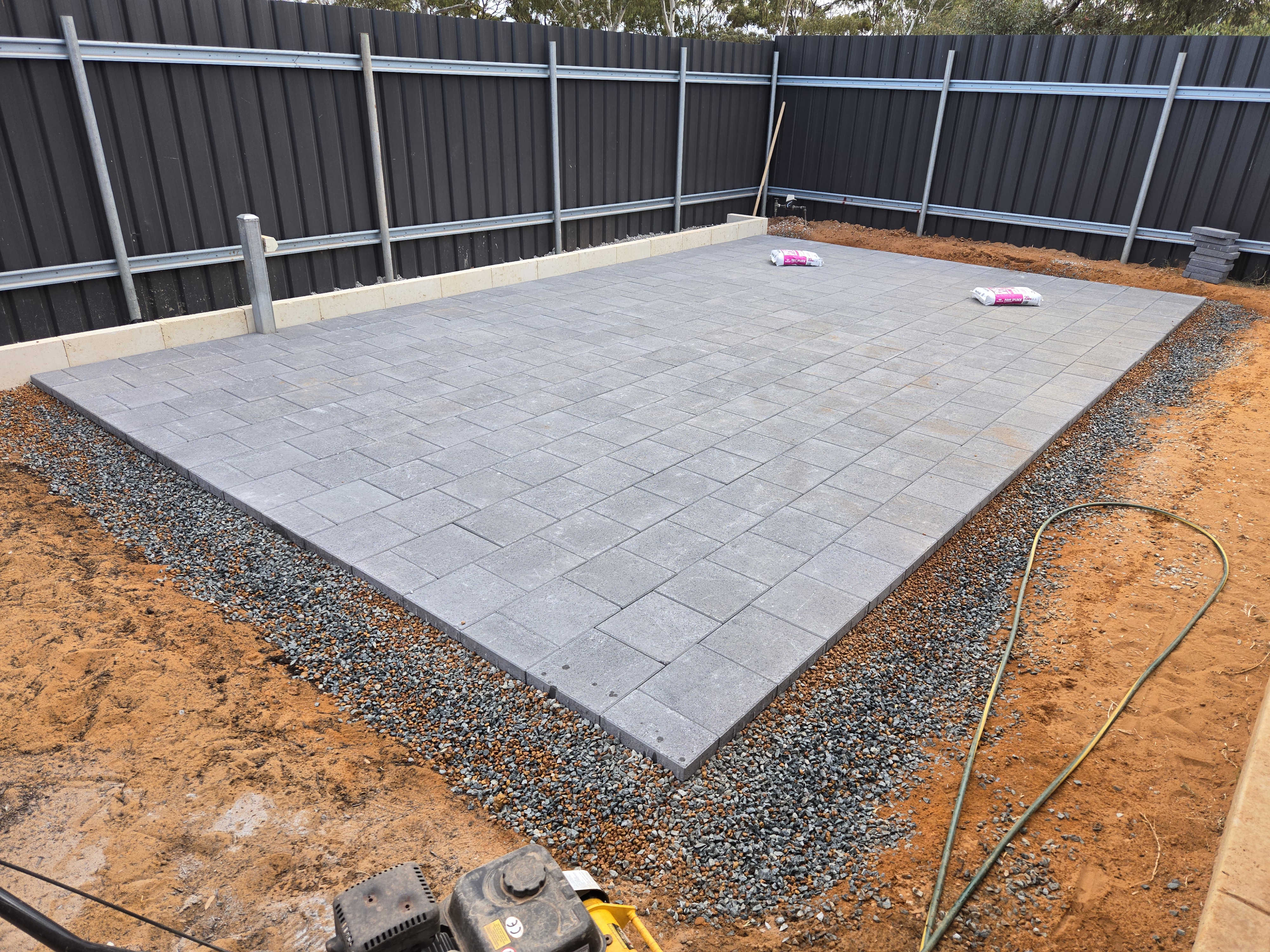 Recent paving job in Kalgoorlie: finished large grey paver patio with Colourbond fencing