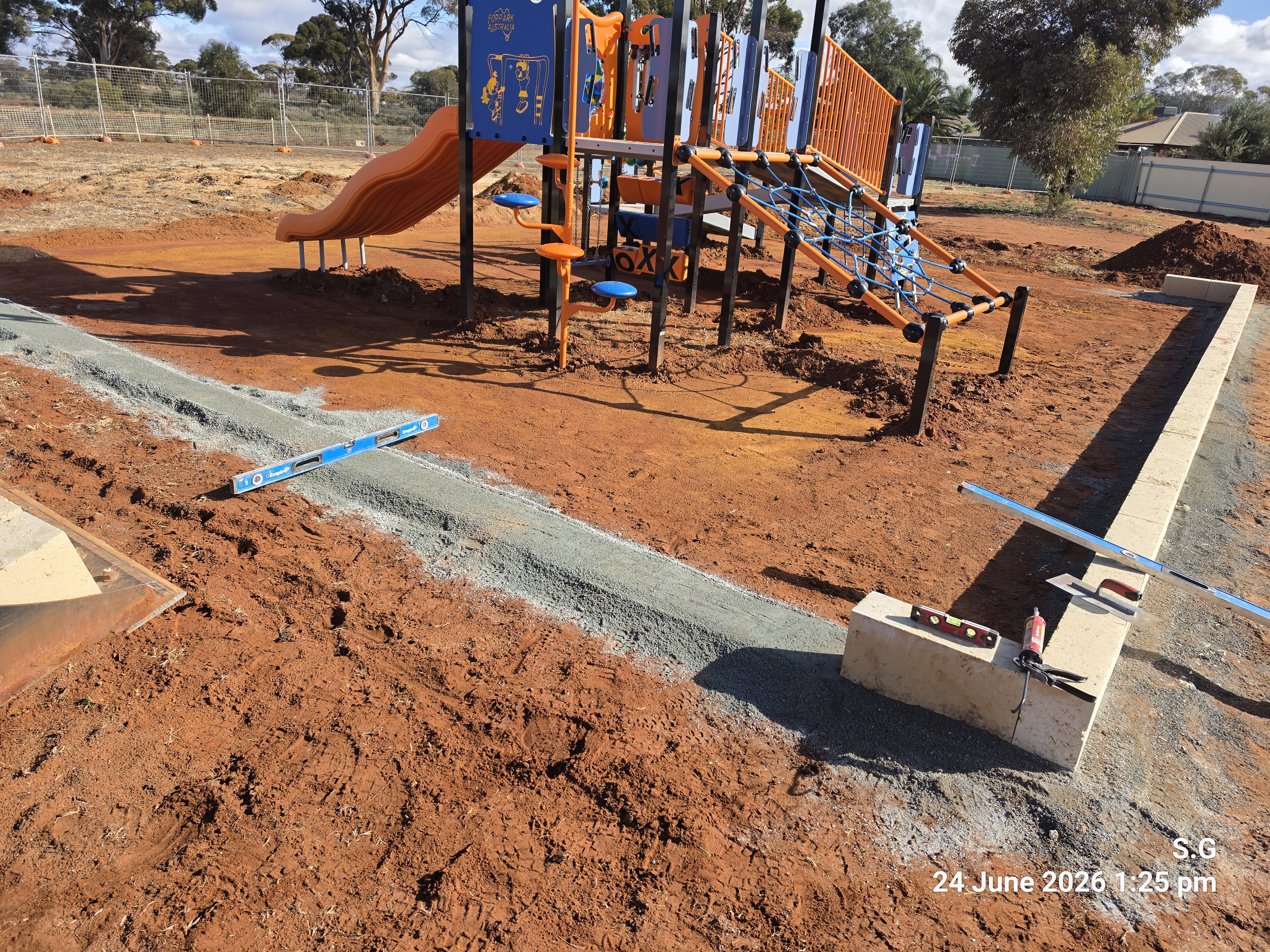 Concrete edging and formwork around playground equipment with spirit levels ensuring precision in the Perth and Goldfields region