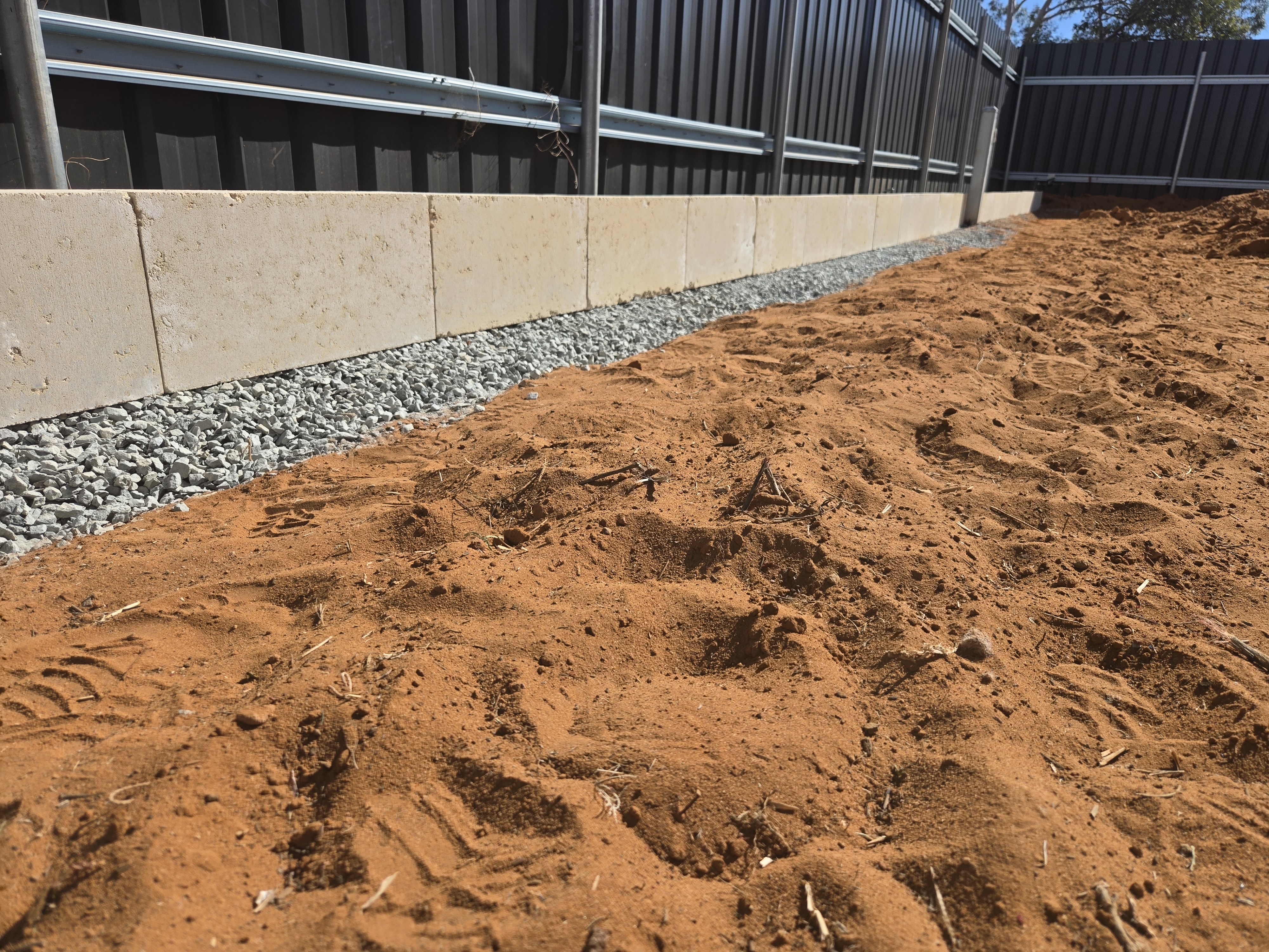 Recent retaining wall job in Kalgoorlie: completed limestone retaining wall with drainage gravel and Colourbond fencing