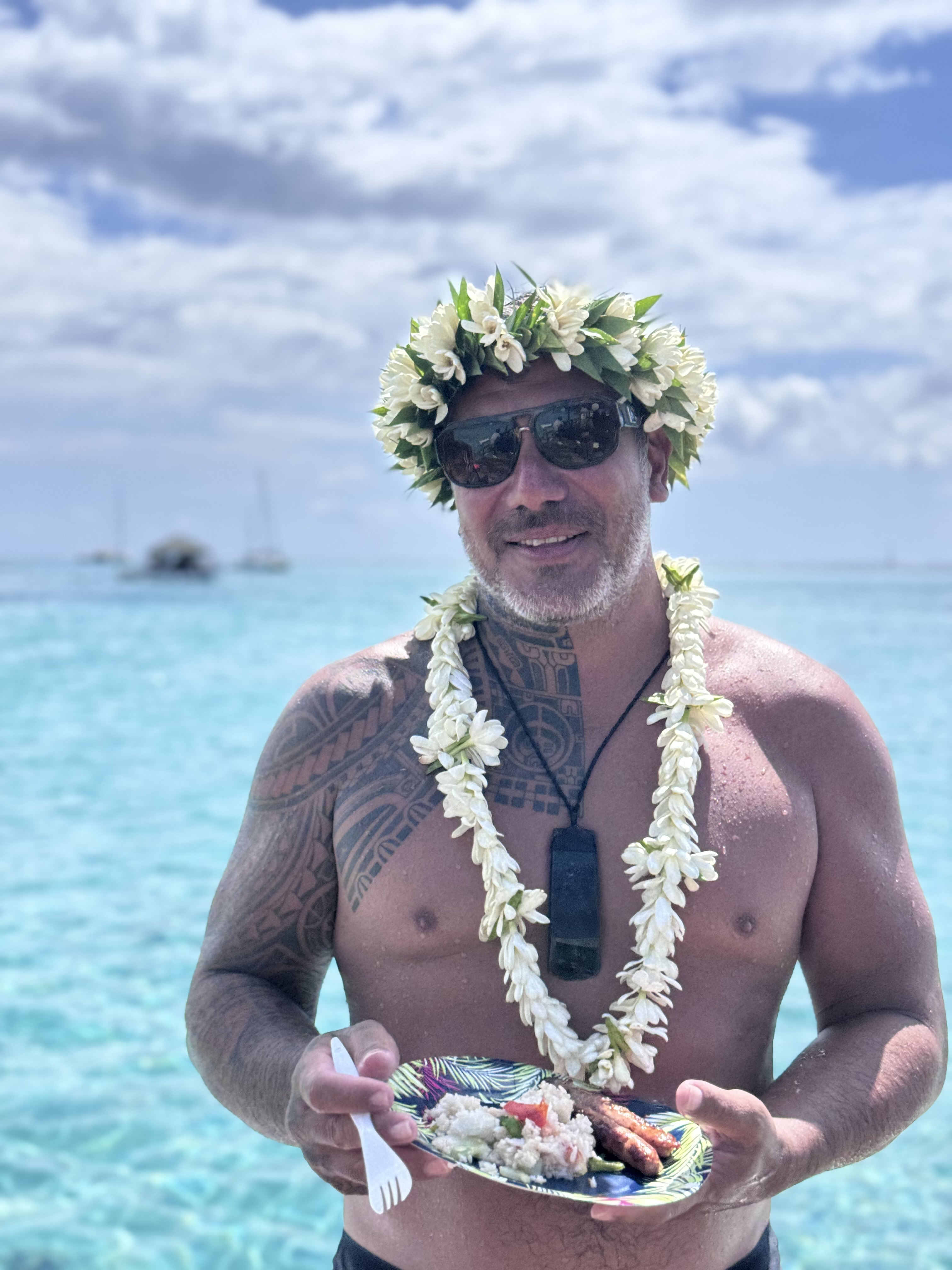 Moanatoa à Tahiti avec couronne et collier de fleurs devant le lagon