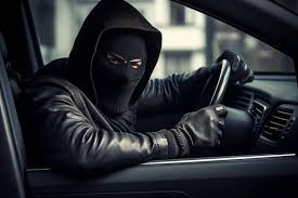 Car thief in mask and hoodie behind the wheel