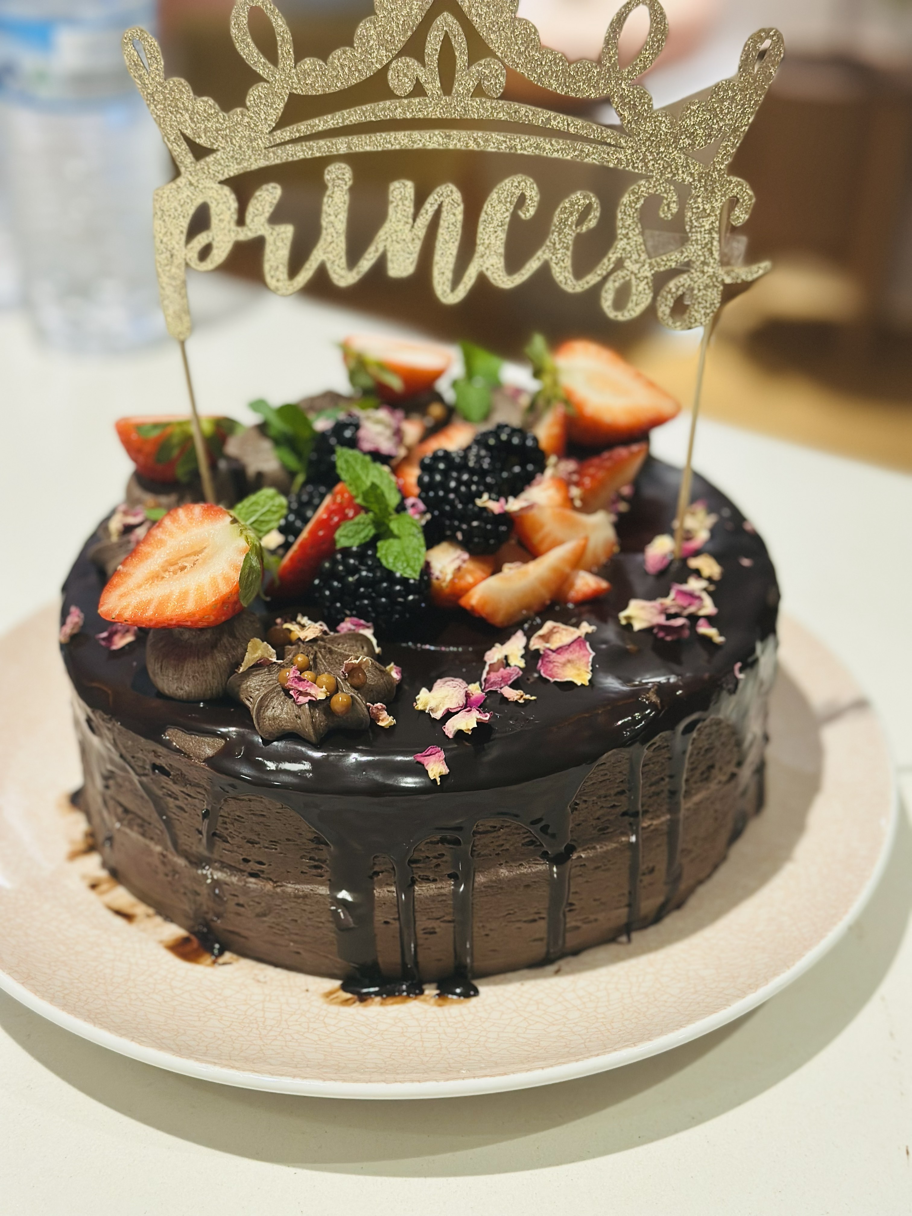 Princess chocolate drip cake with berries and rose petals