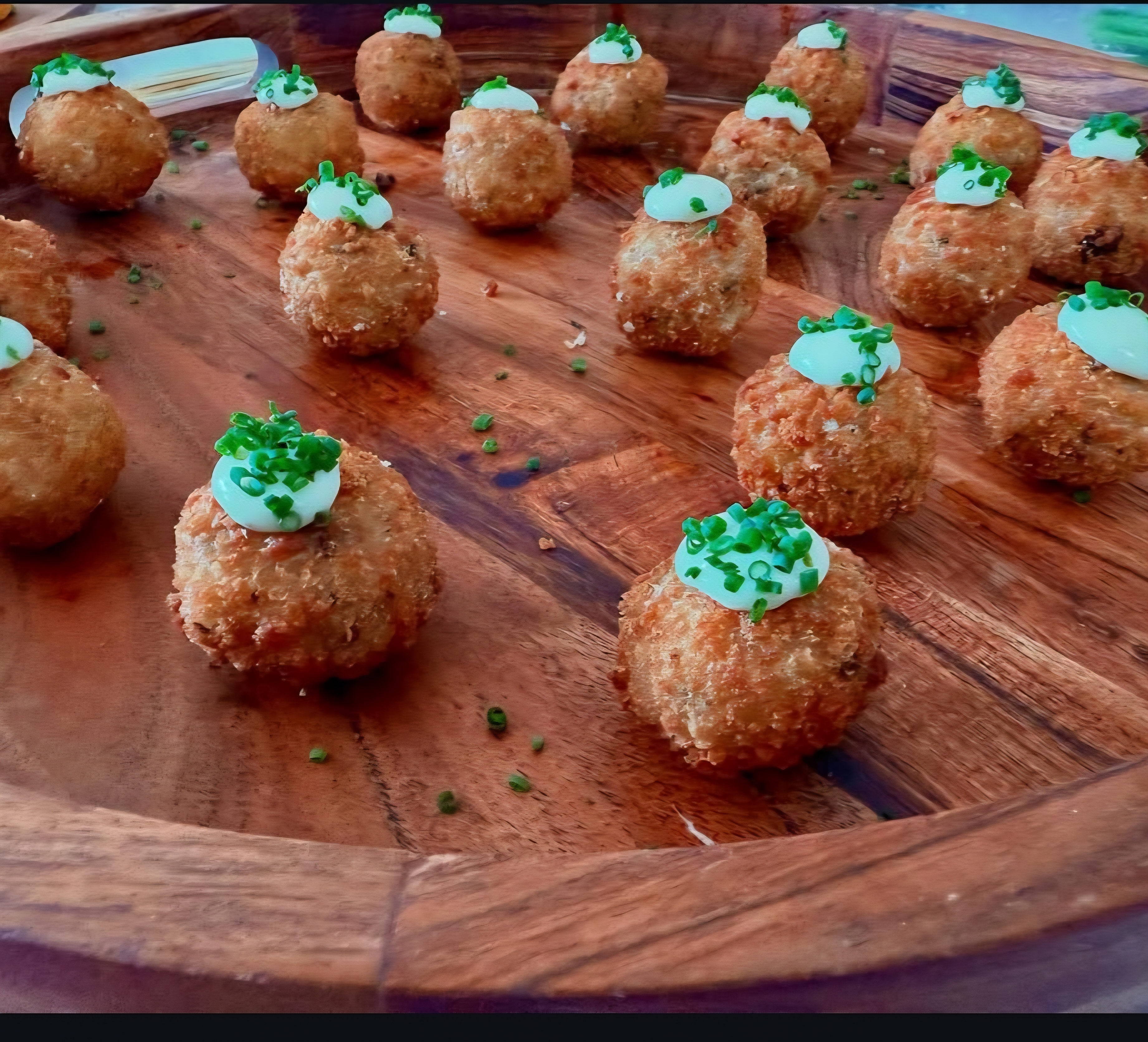 Arancini with aioli and chives on wooden platter
