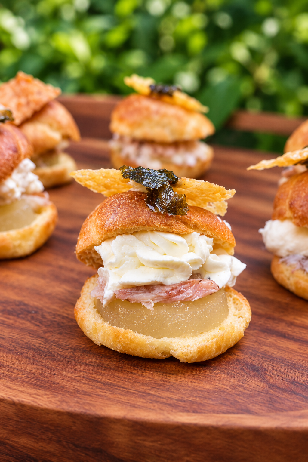 Gourmet choux buns with custard, cream and crispy garnish on timber board