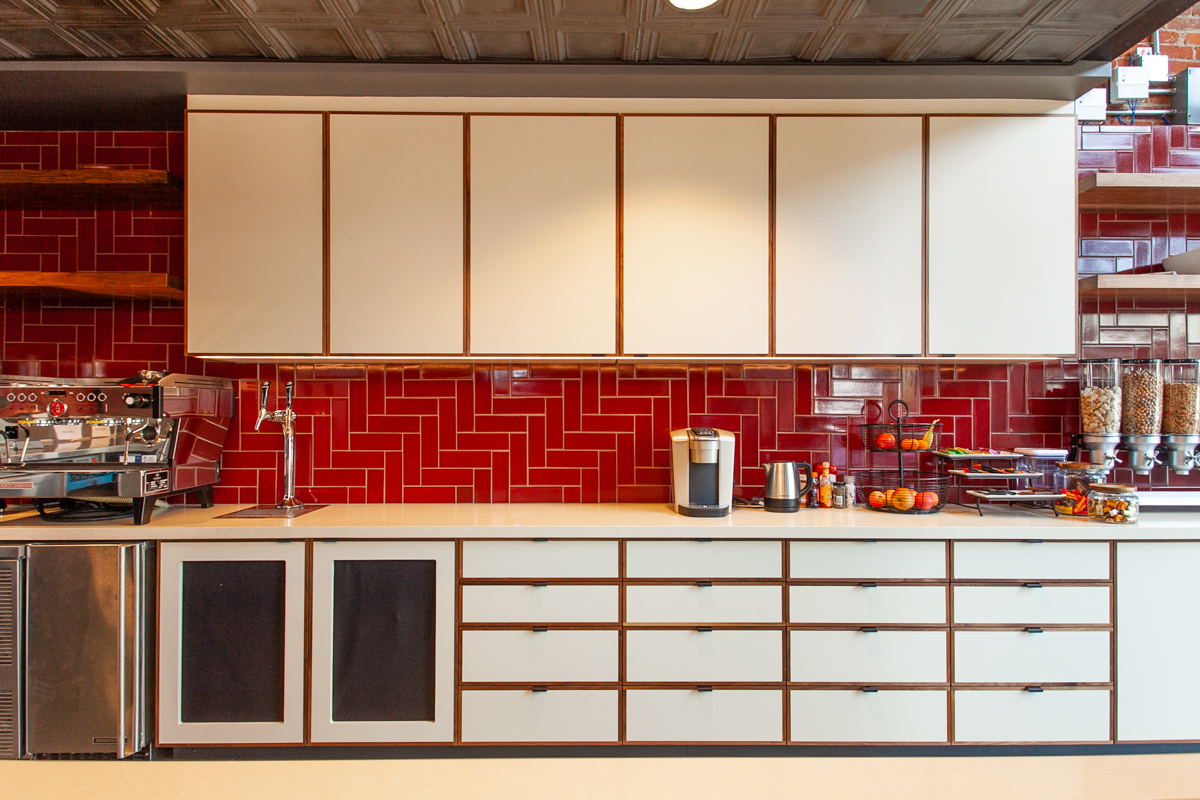 Detail view of white HPL upper cabinets with solid walnut edgebanding and solid walnut floating shelves installed by California Woodworking for Newco Los Angeles