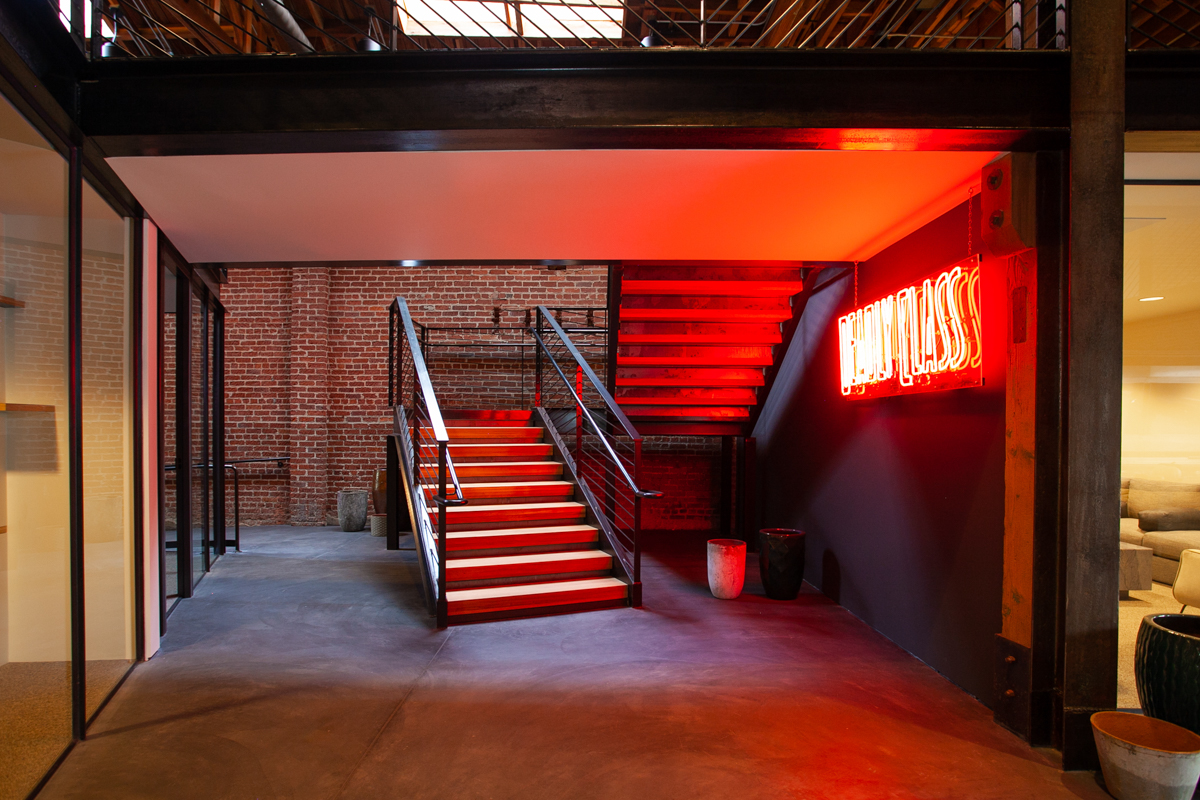 Custom solid white oak stair treads installed by California Woodworking for Newco at 1117 San Pedro Street Los Angeles with neon World Class sign