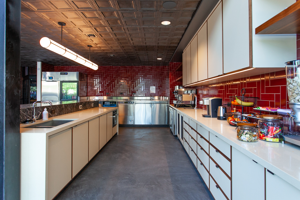 Full view of commercial kitchen cabinetry installation with HPL and solid walnut edgebanding for Newco at 1117 San Pedro Street Los Angeles
