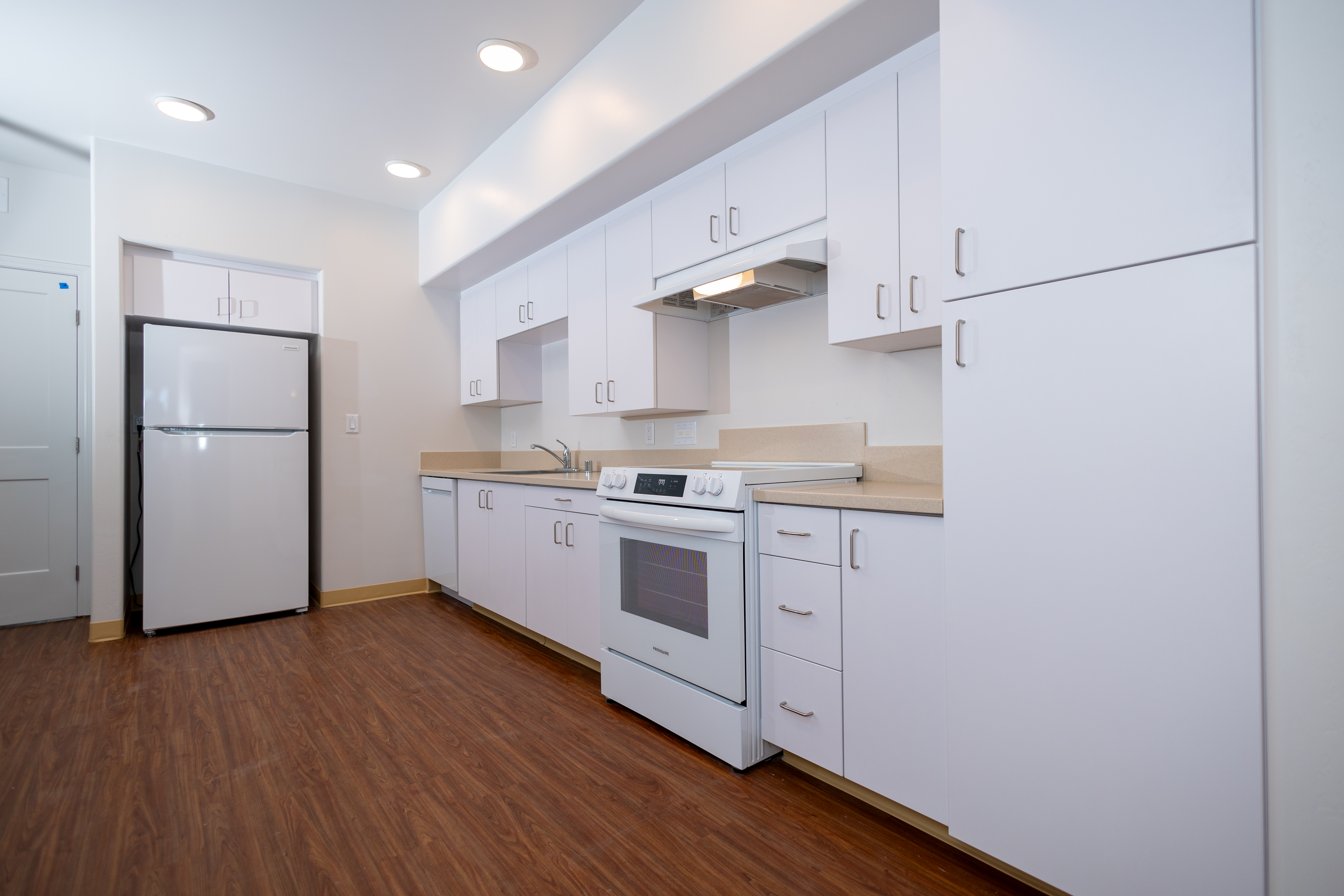 Kitchen cabinetry with white slab doors and light countertops installed in all 50 units at Pismo Terrace apartment complex in Pismo Beach CA by California Woodworking
