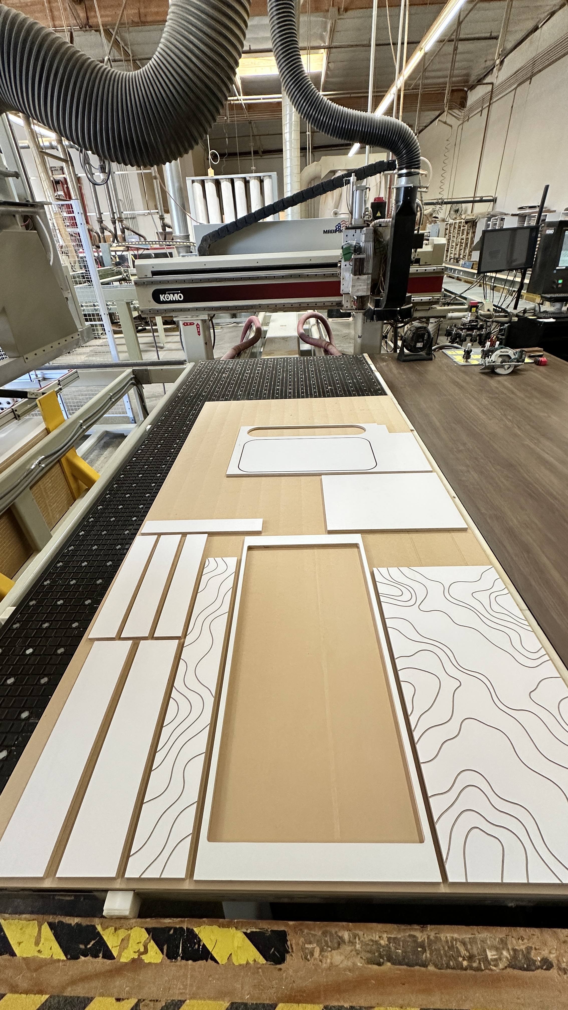 KOMO CNC router cutting nested cabinet parts from a full sheet in our Oxnard shop